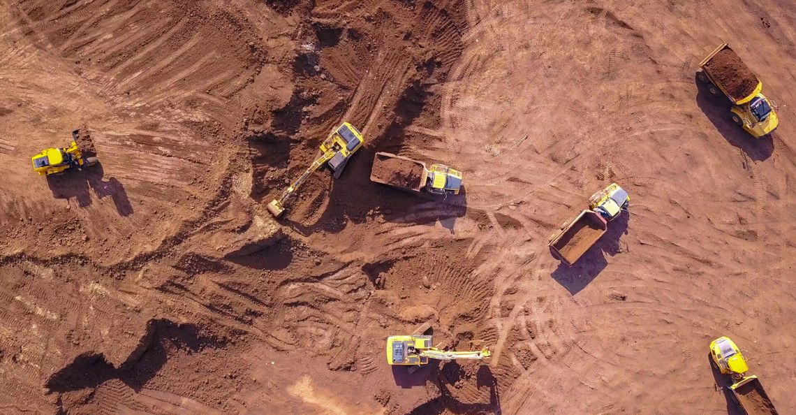 Earthmoving equipment. Aerial view of large construction site with several earthmover machines.